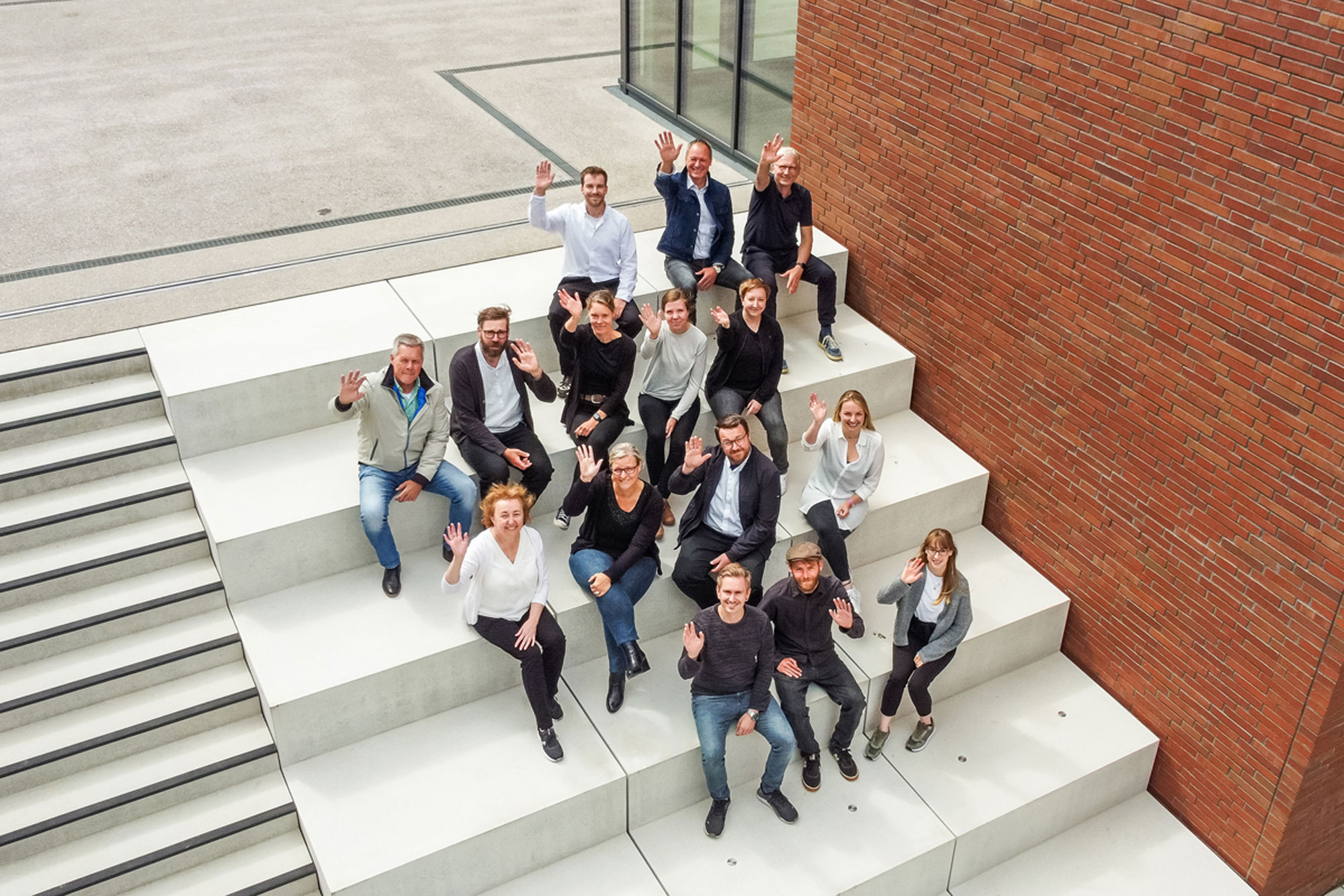 Blick von oben auf das fRp-Team (sitzt auf einer Treppe und winkt)